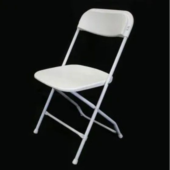 A white folding chair is sitting on a black background.