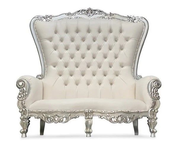 A white and silver tufted couch on a white background.
