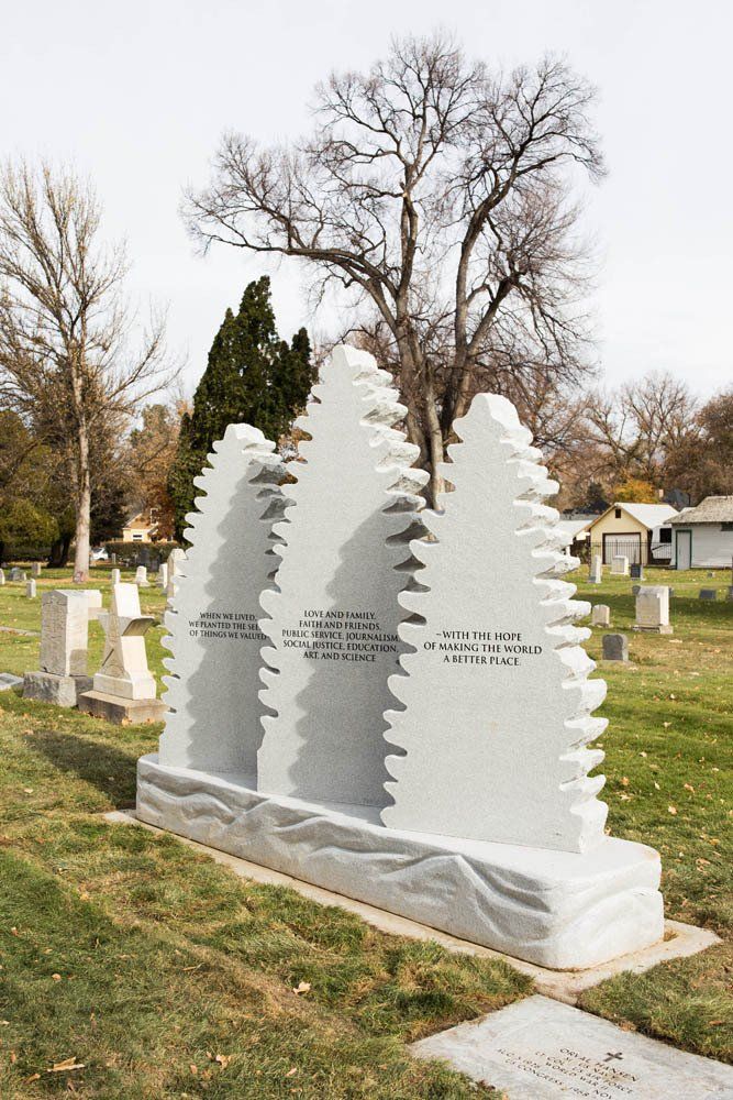 Three unique pine tree-shaped white granite headstones with engraved inspirational messages about love, family, values, and hope, set in a peaceful cemetery.