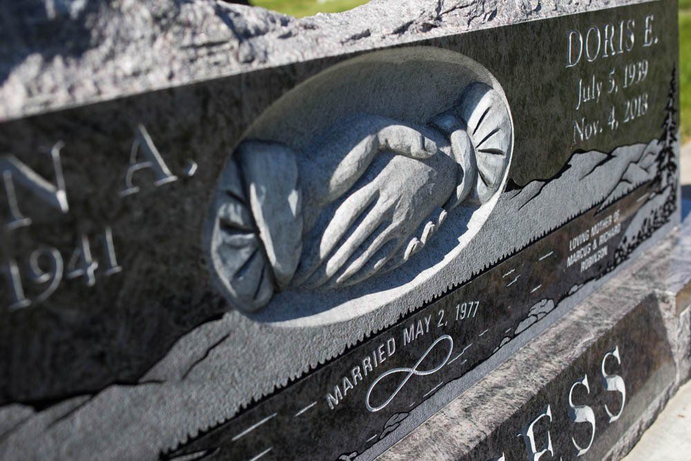 Detailed close-up of two carved hands clasped in a handshake with surrounding engraving, representing unity and eternal connection.