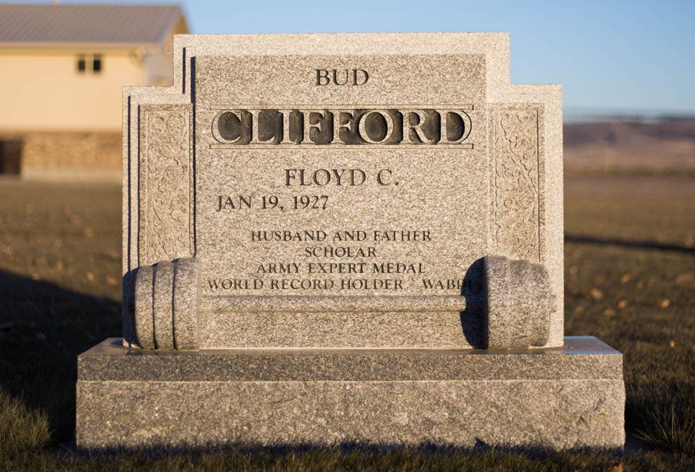 Close-up of the Clifford headstone showing clear engraved lettering and a smooth granite finish under golden hour lighting.