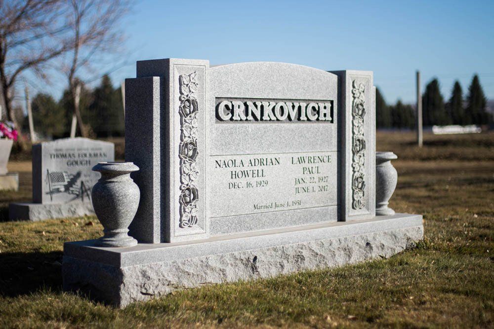 Side view of Crnkovich family monument with classic floral corner carvings and urn decor