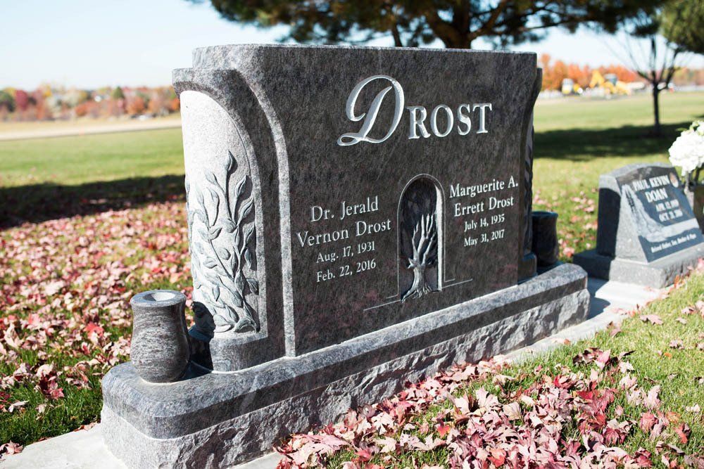 Curved granite memorial for Dr. Jerald Drost featuring floral engraving and name inscription