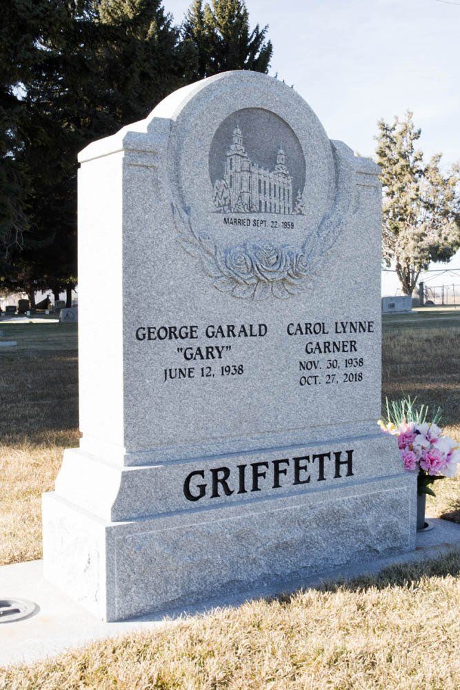 Angled view of Griffeth headstone with surname carving and floral design on gray granite
