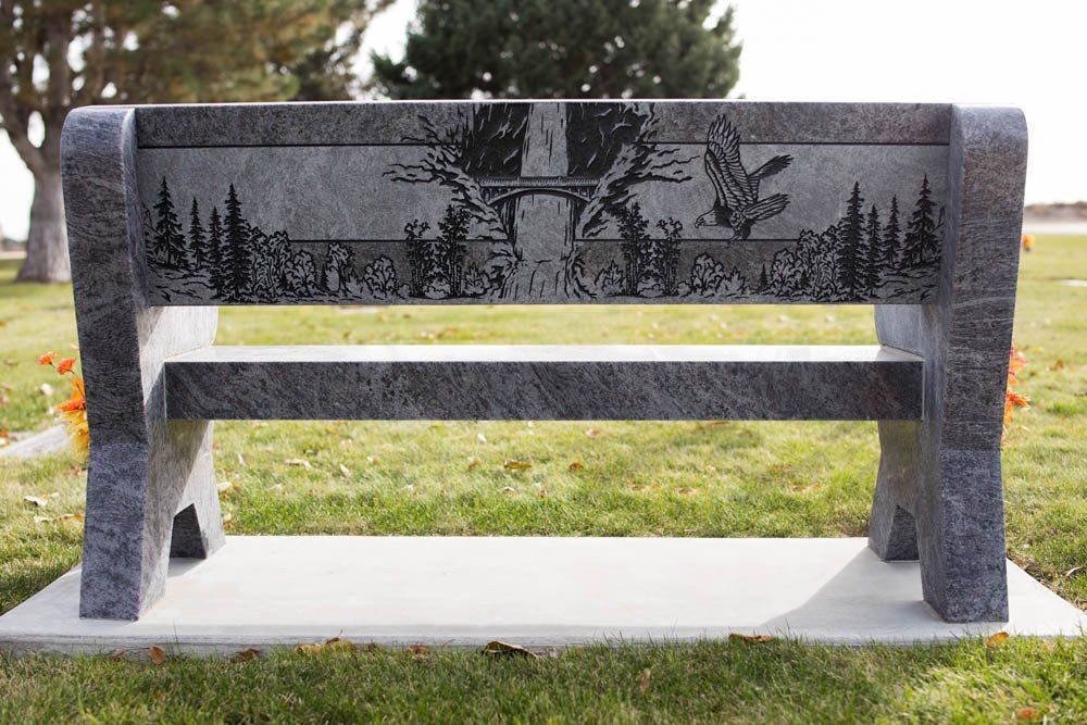 Gray granite memorial bench for Herrera family with detailed hunting scene and wildlife engraving