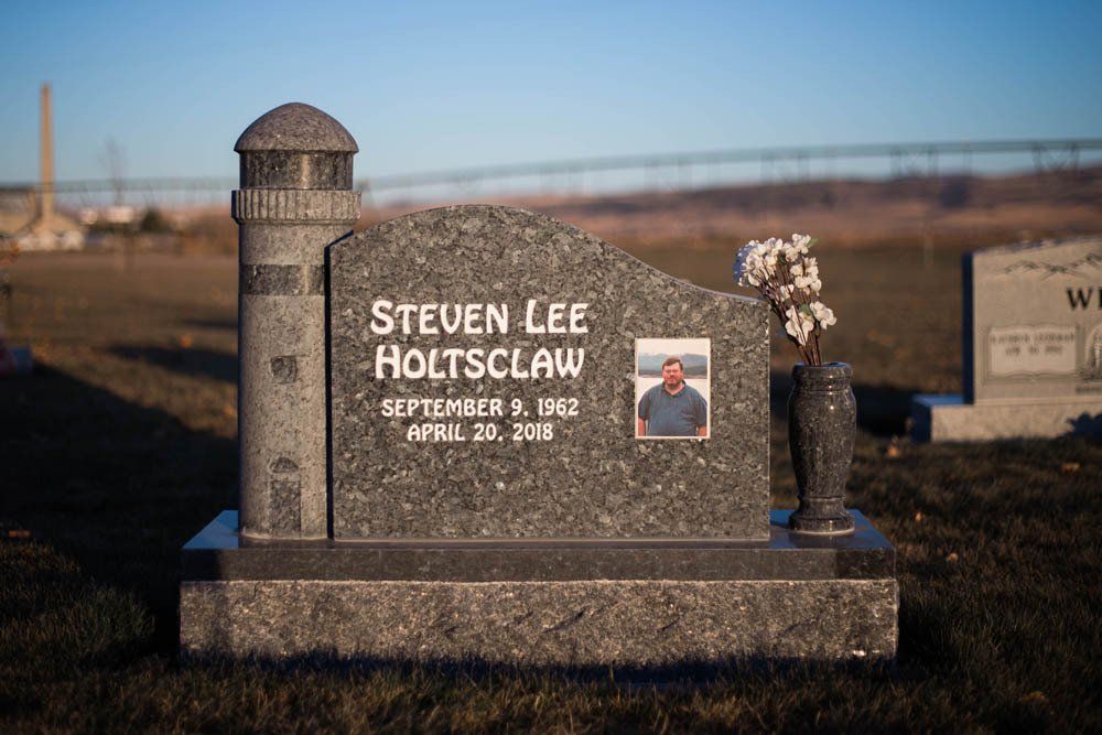 Traditional granite headstone for Steven Lee Holtsclaw with red cross, dates, and a photo