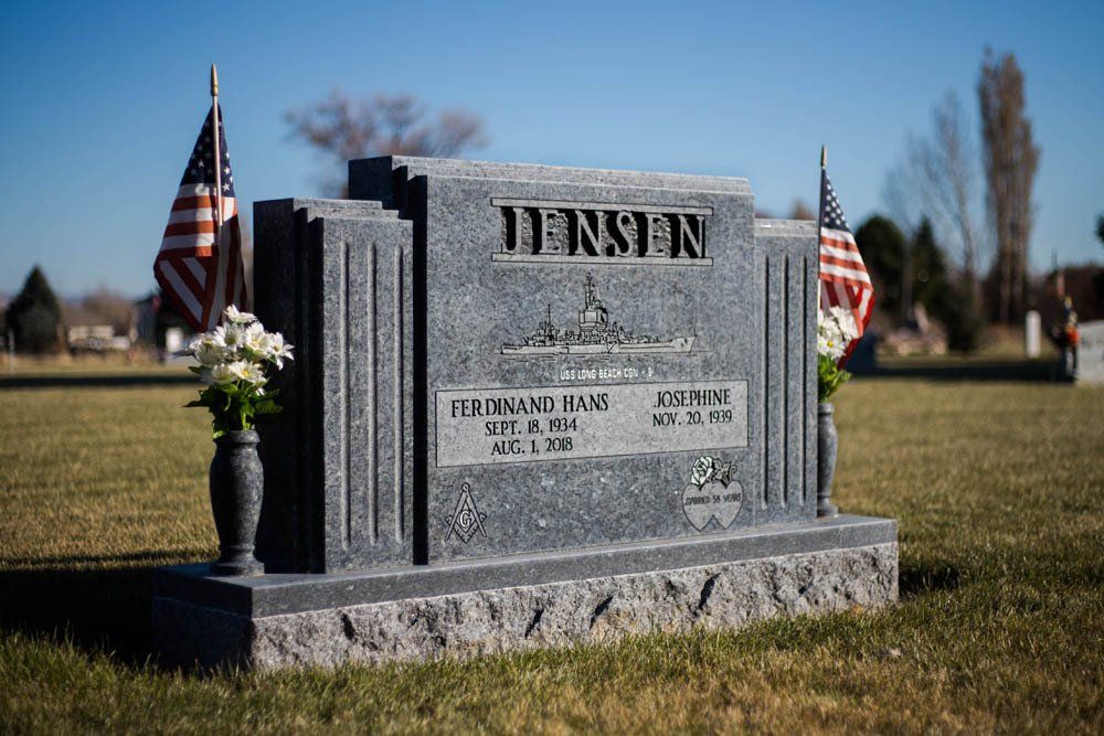 Gray granite memorial for Jensen family featuring traditional column-style sides and floral decor