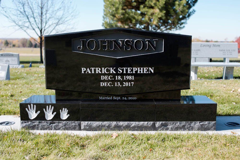 Black granite headstone for Patrick Stephen Johnson with name engraving and decorative handprints