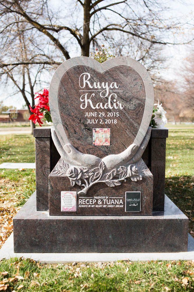 Close-up of Ruya Kadir’s heart-shaped headstone with decorative hands, Arabic text, and family inscriptions