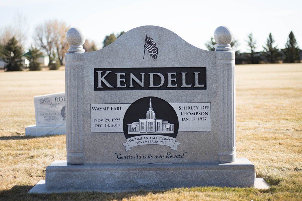 Gray granite Kendell family headstone featuring Latter-day Saint temple engraving and patriotic flag