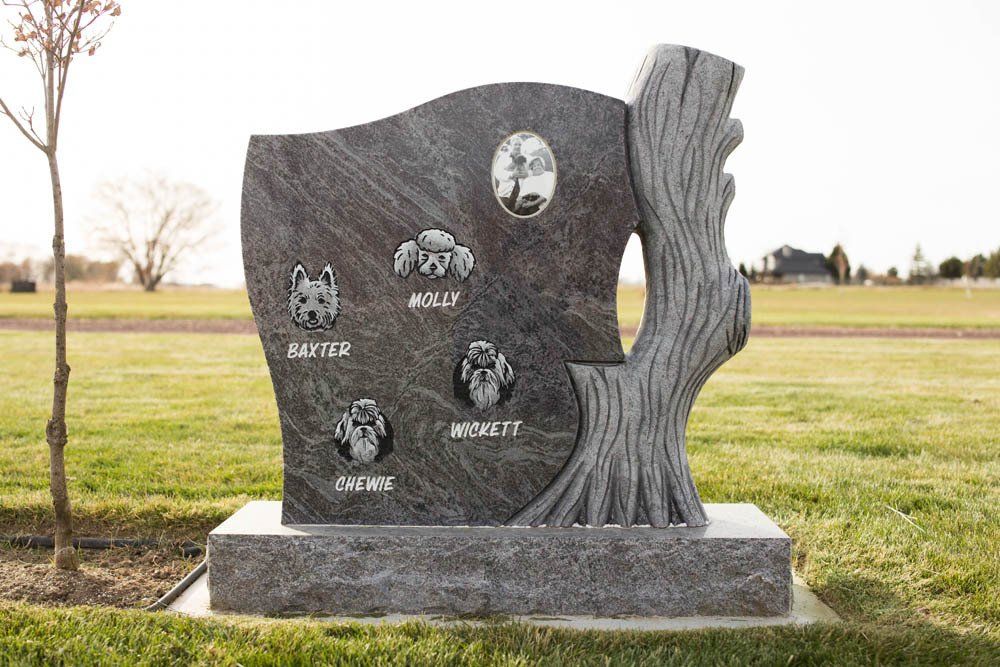 Pet memorial stone featuring engraved portraits and names of Baxter, Molly, Chewie, and Wickett