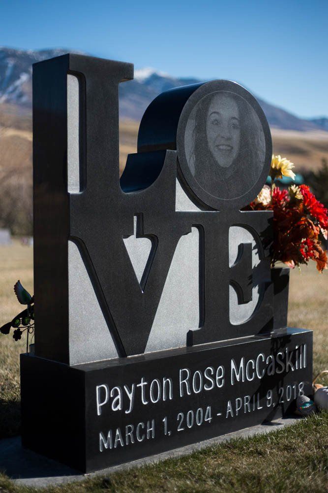 Close-up of artistic black granite monument spelling “LOVE” with floral arrangement