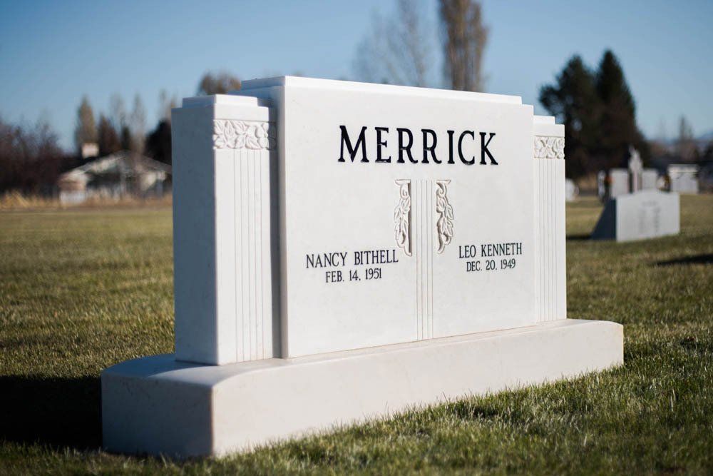 White granite headstone for Nancy Bithell and Leo Kenneth Merrick with classic column-style carvings
