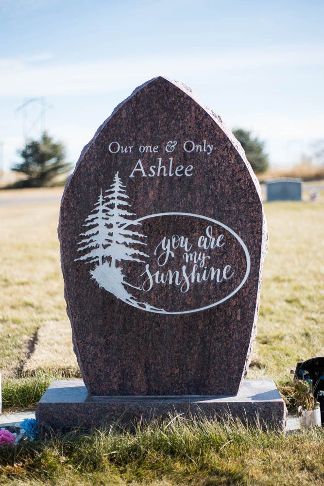 Red granite memorial with silhouette pine tree design and “You Are My Sunshine” inscription for Ashlee
