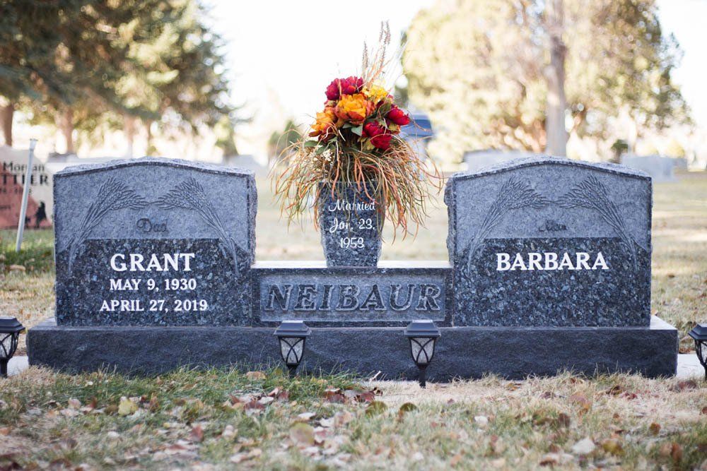 Front view of Neibaur family headstone with two name panels, flower vase, and engraved wheat motifs