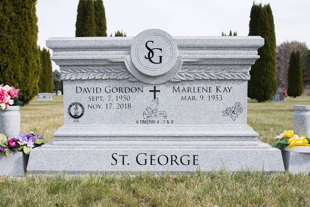Front view of light gray granite monument with SG crest and floral engravings for the St. George family