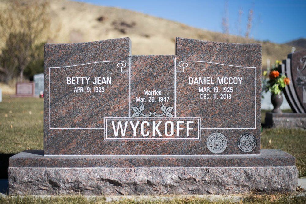 Engraved double granite headstone for Betty Jean and Daniel McCoy with the surname Wyckoff in a cemetery setting