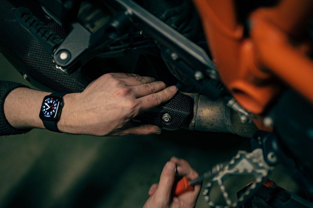 Hands adjusting a rifle in a dark, close-up scene with a wristwatch visible