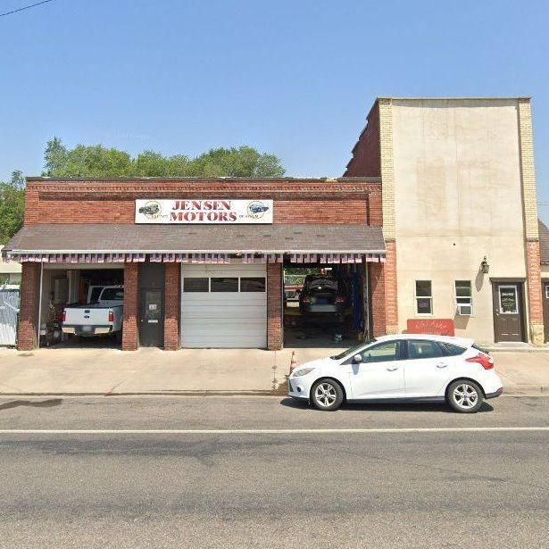 A white car is parked in front of a jensen motors garage