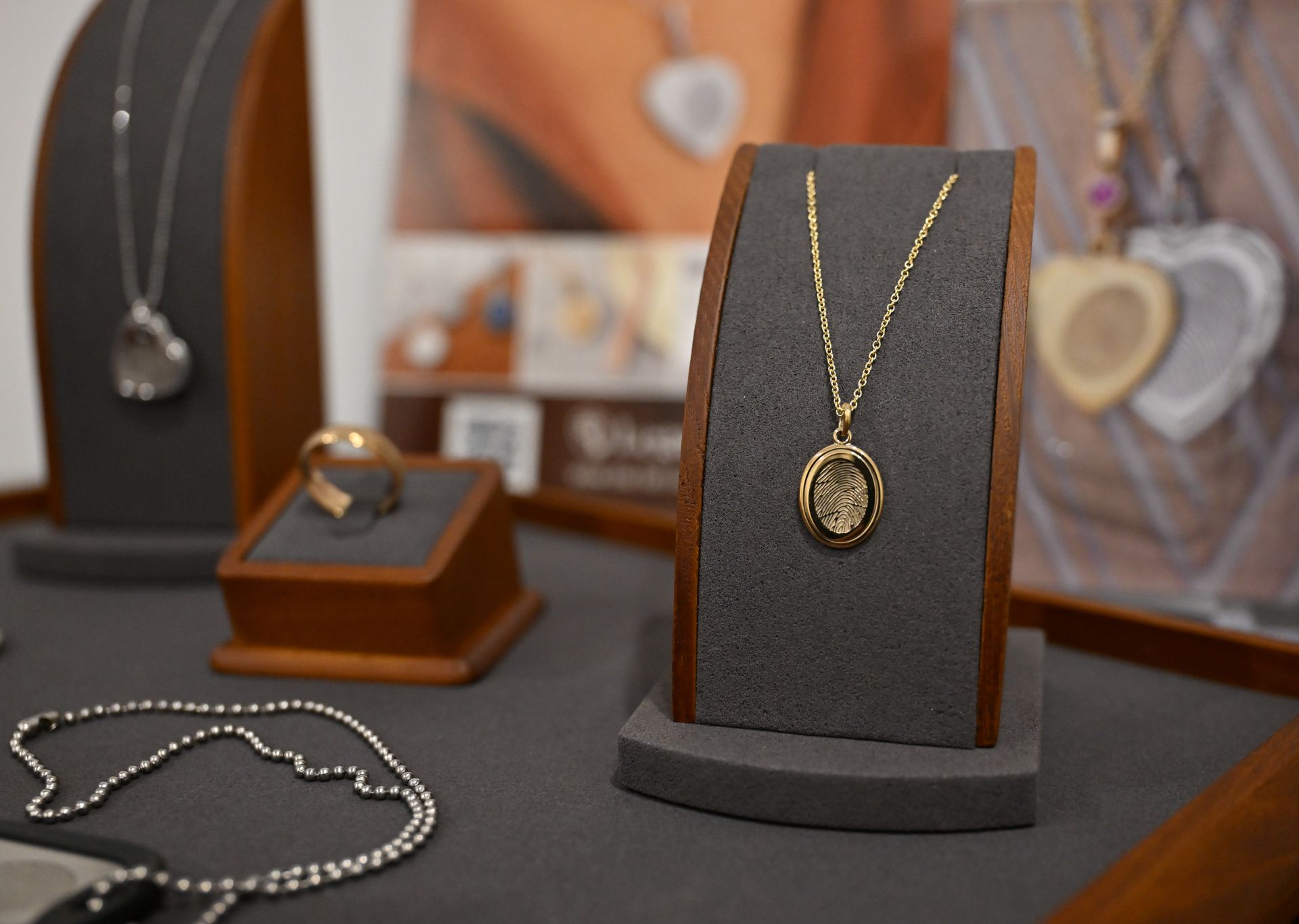 Gold necklace and jewelry displayed on black velvet stands in a store showcase.