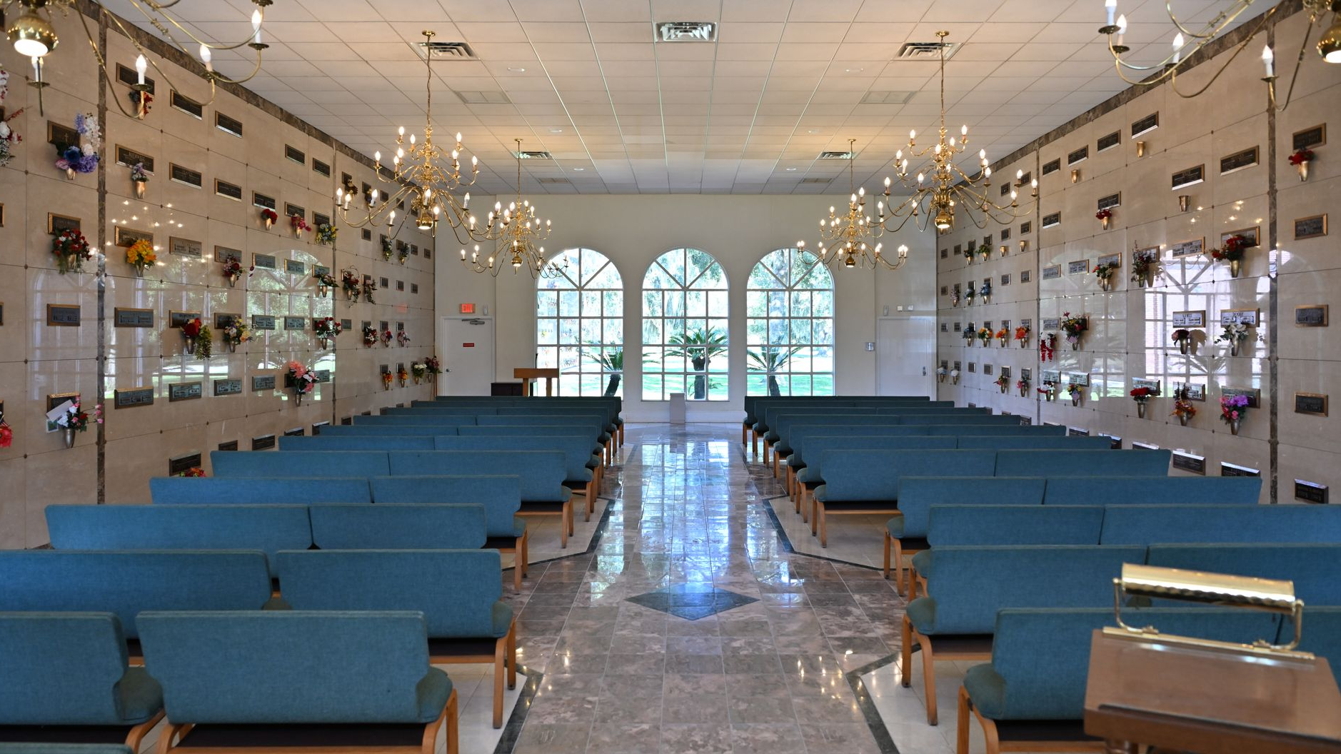 Bright church interior with blue pews, aisle, and arched windows at the front