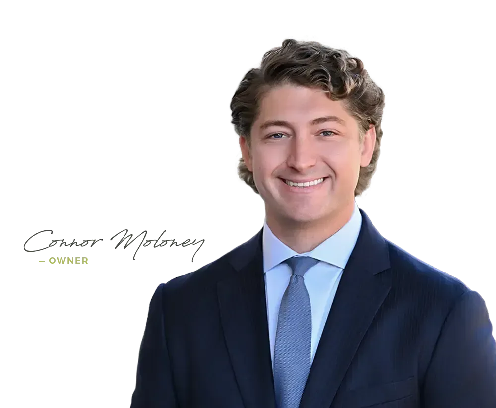 Portrait of a smiling professional in a navy suit and blue tie on a white background, with a signature logo and “OWNER” text