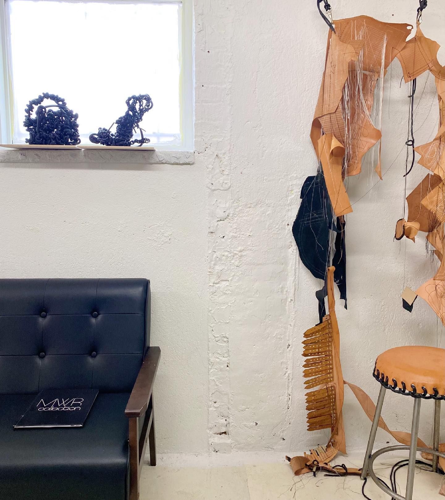 A chair and a stool in a room with a window in the MWR Atelier