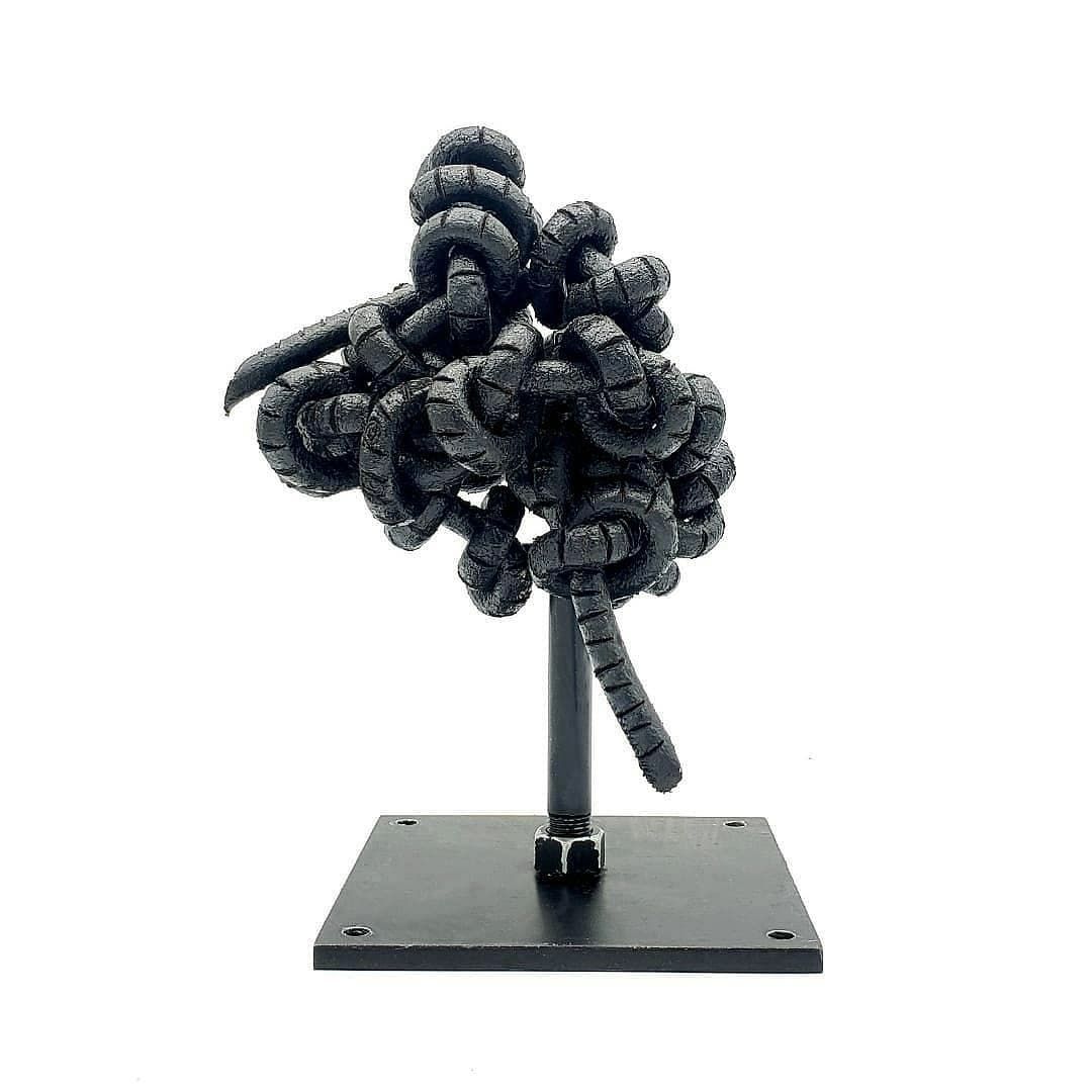 A black sculpture of a tree on a stand on a white background.