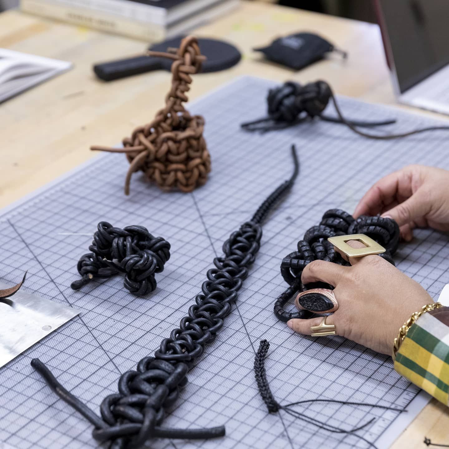 A person is working on a piece of jewelry on a cutting board