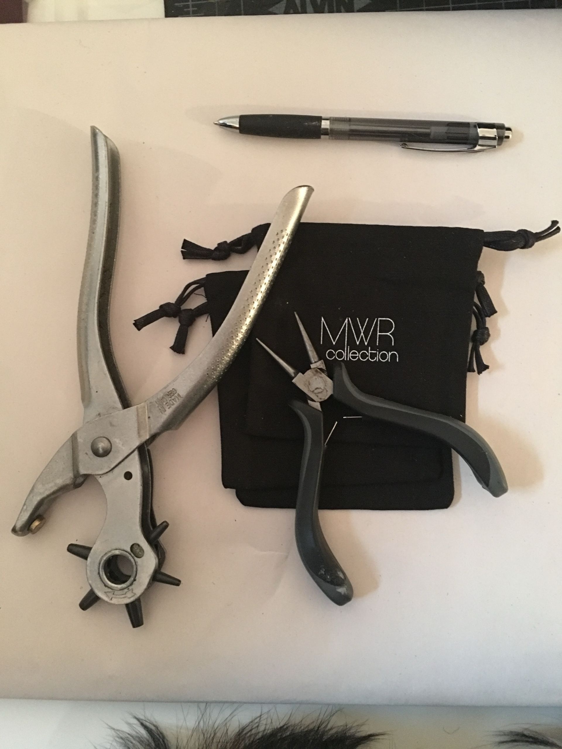 A pair of pliers sitting on top of a table next to a hole puncher