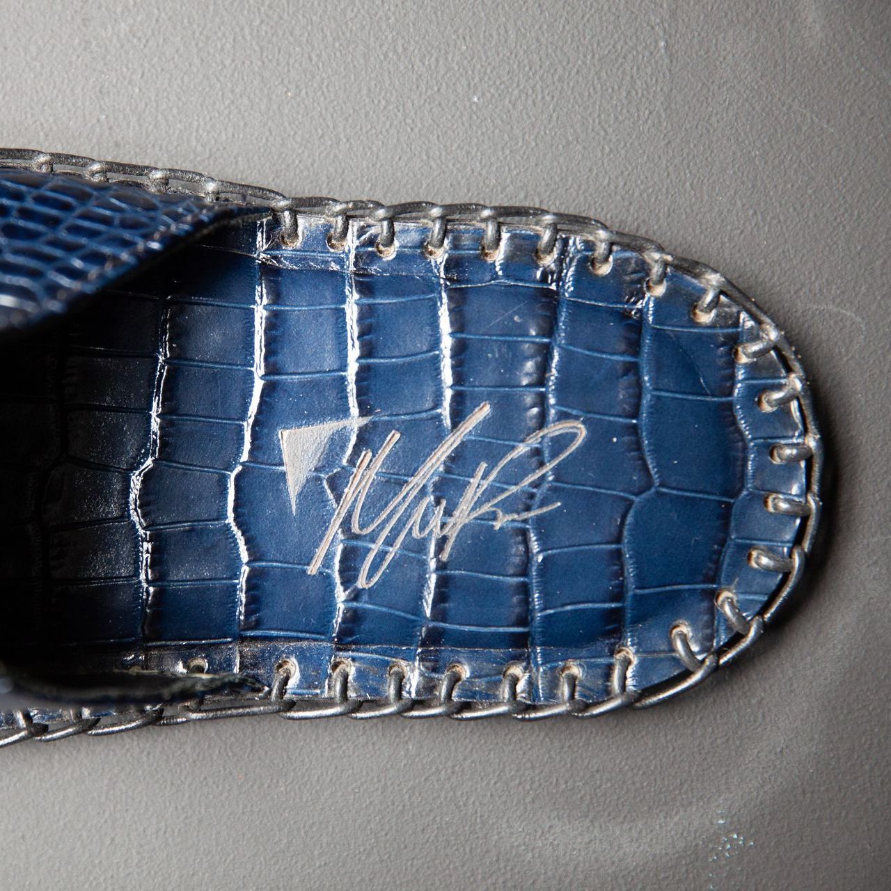 A close up of a blue slipper with a signature on it