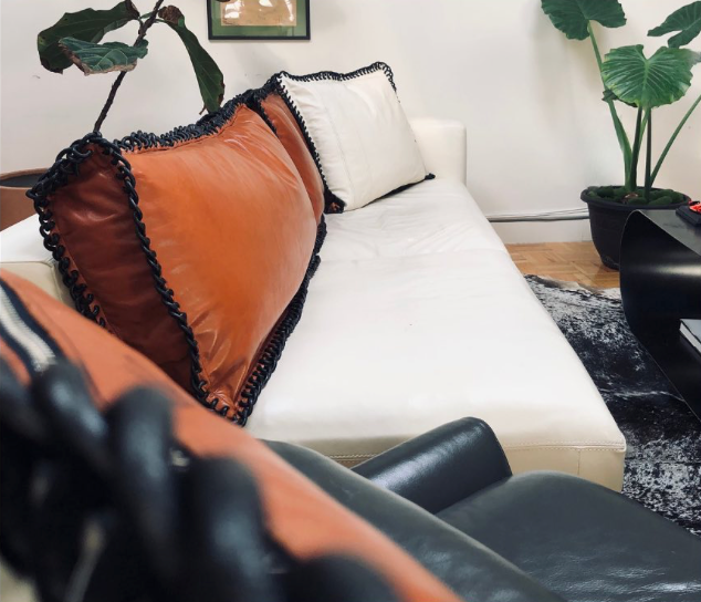 A living room with a white couch and orange pillows