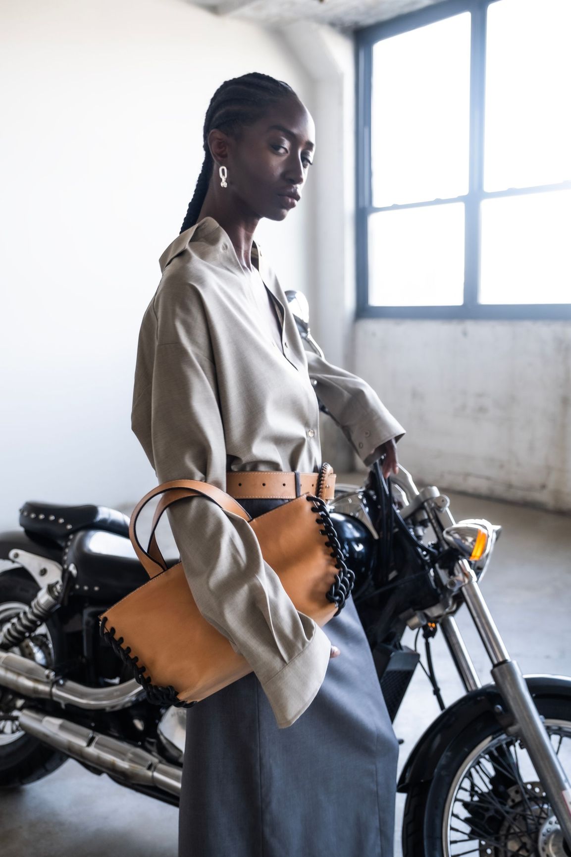 A woman is standing next to a motorcycle in a garage.