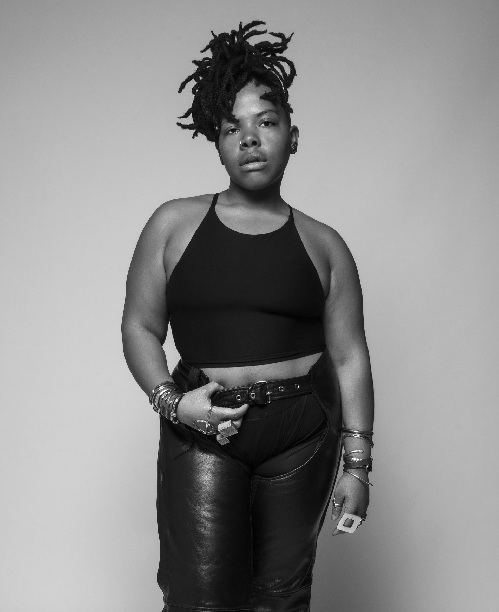 A black and white photo of a woman wearing a crop top and leather pants
