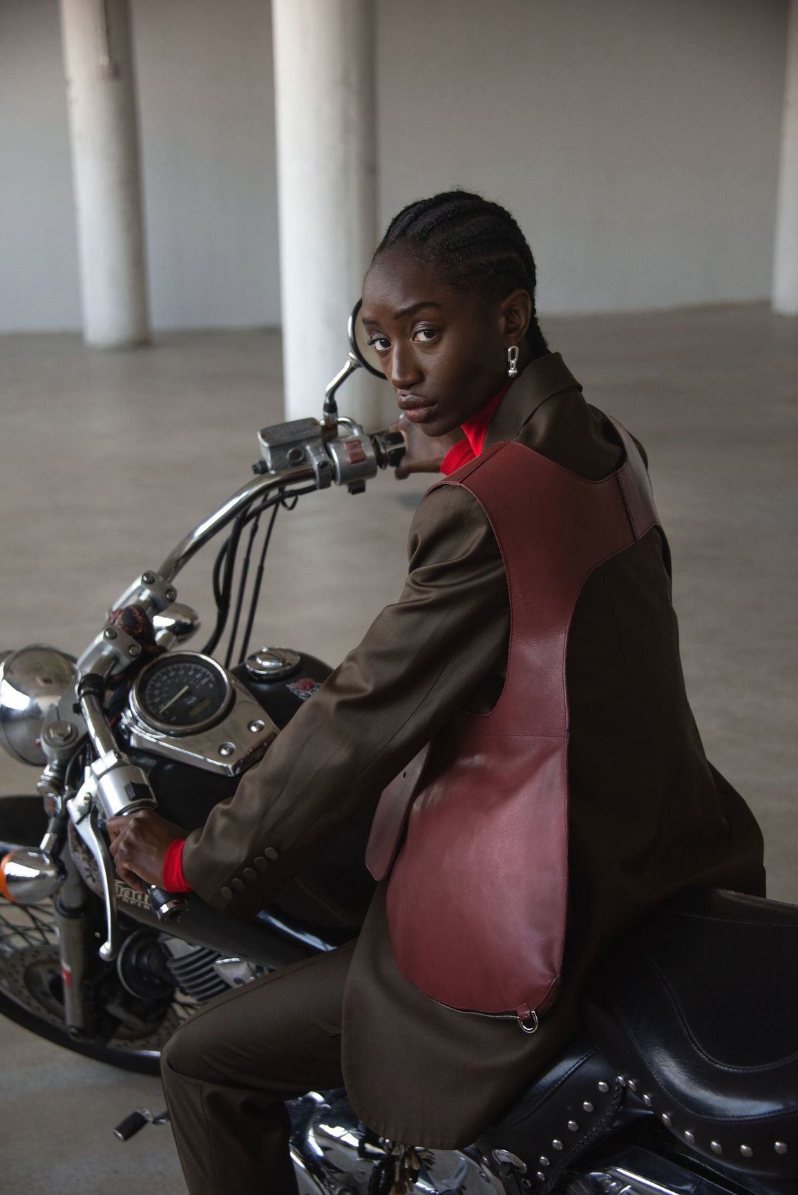 A woman is sitting on a motorcycle in a garage.