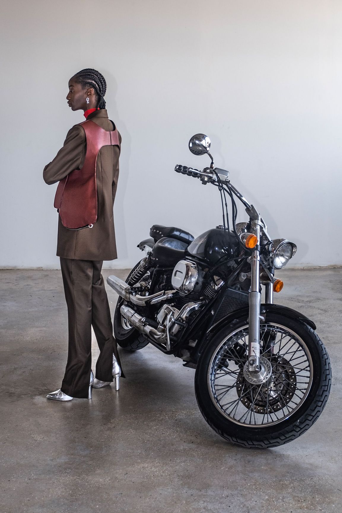 A woman is standing next to a motorcycle in a garage.