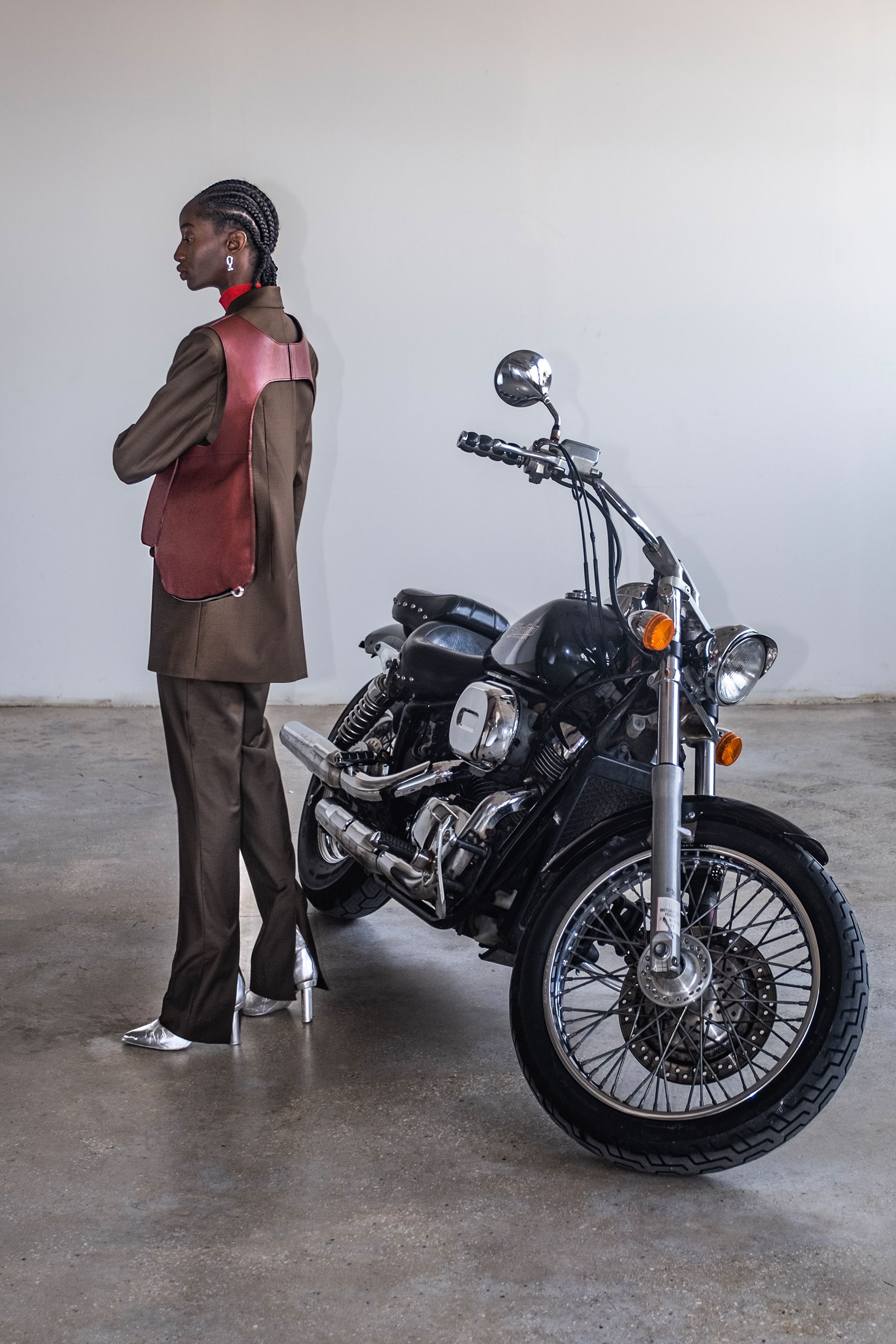 A woman is standing next to a motorcycle in a garage.