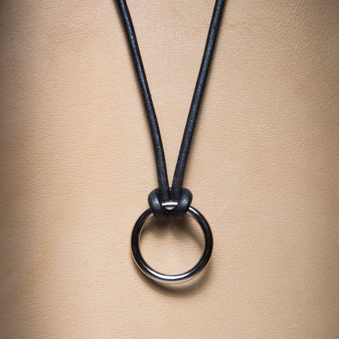 A black necklace with a silver ring on it