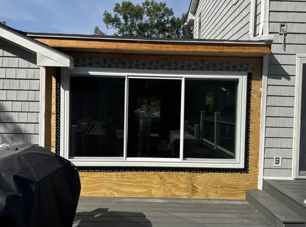Window installation in progress on a house with gray siding.