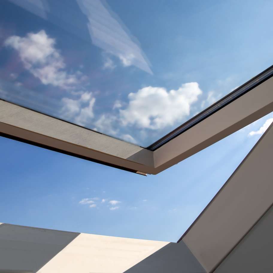 Skylight looking up at a bright blue sky with white clouds.