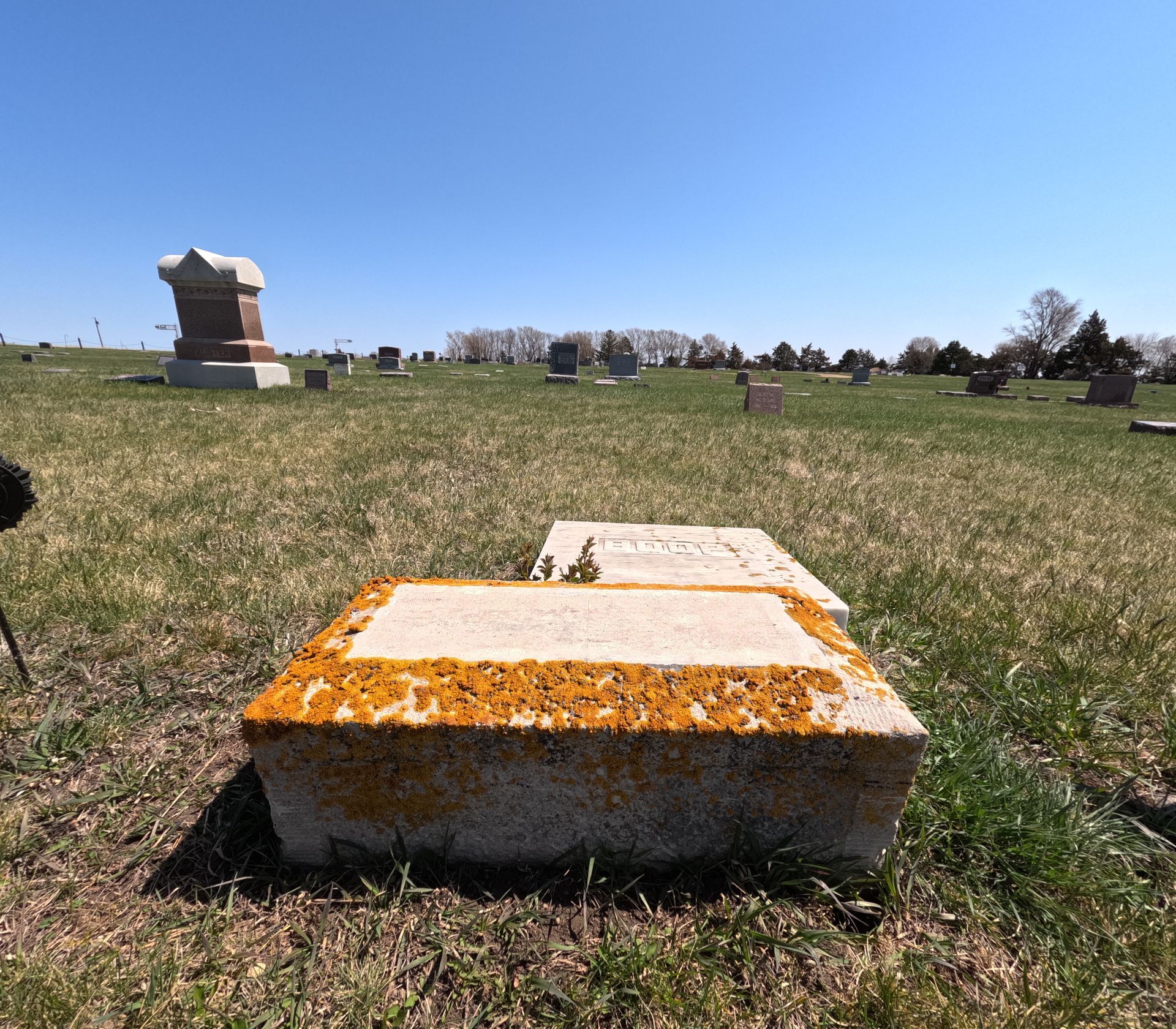 A grave in a cemetery with a gravestone tipped over