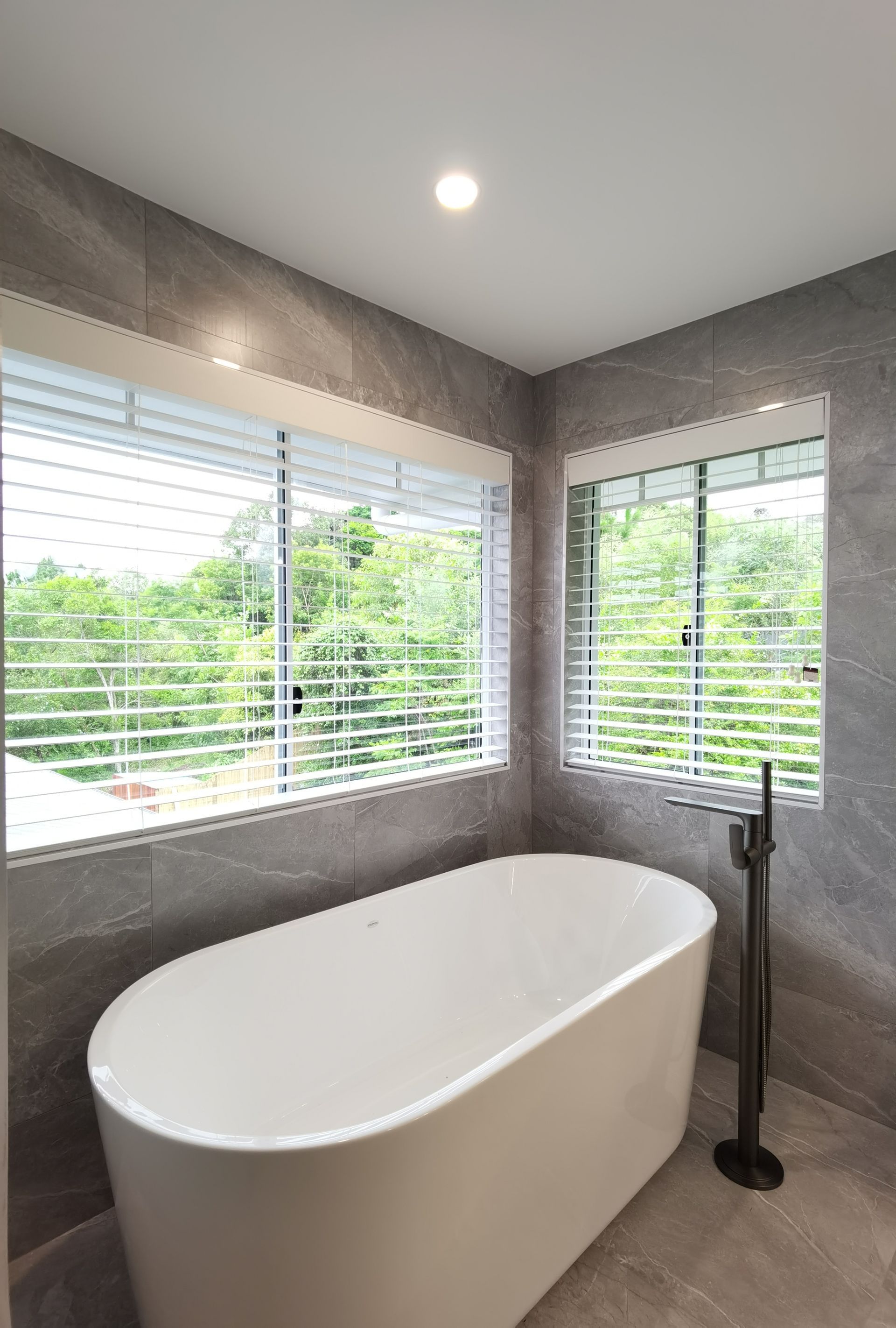 A bathroom with a bathtub and a window with blinds.