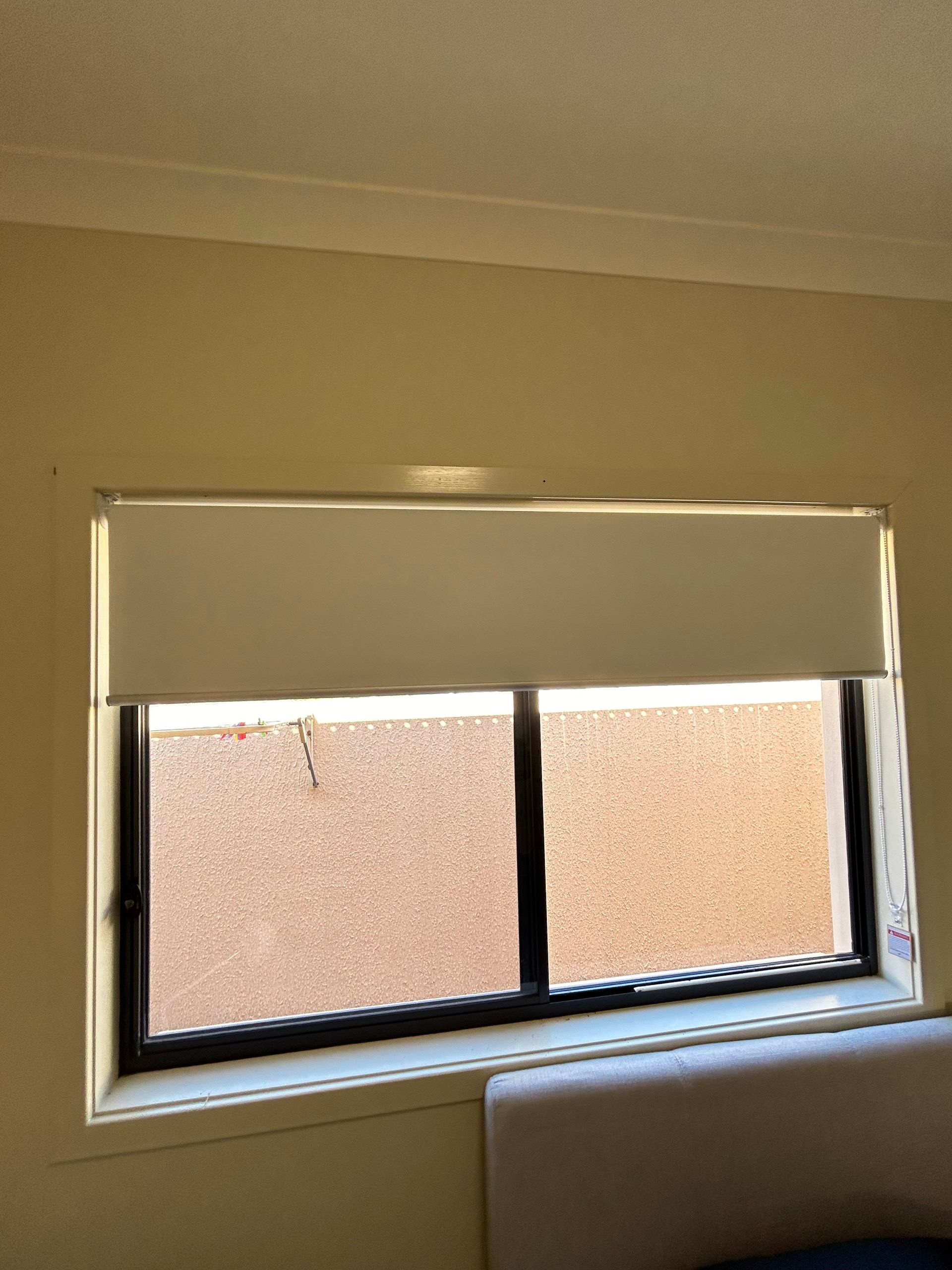 A bedroom with a large window with blinds on it