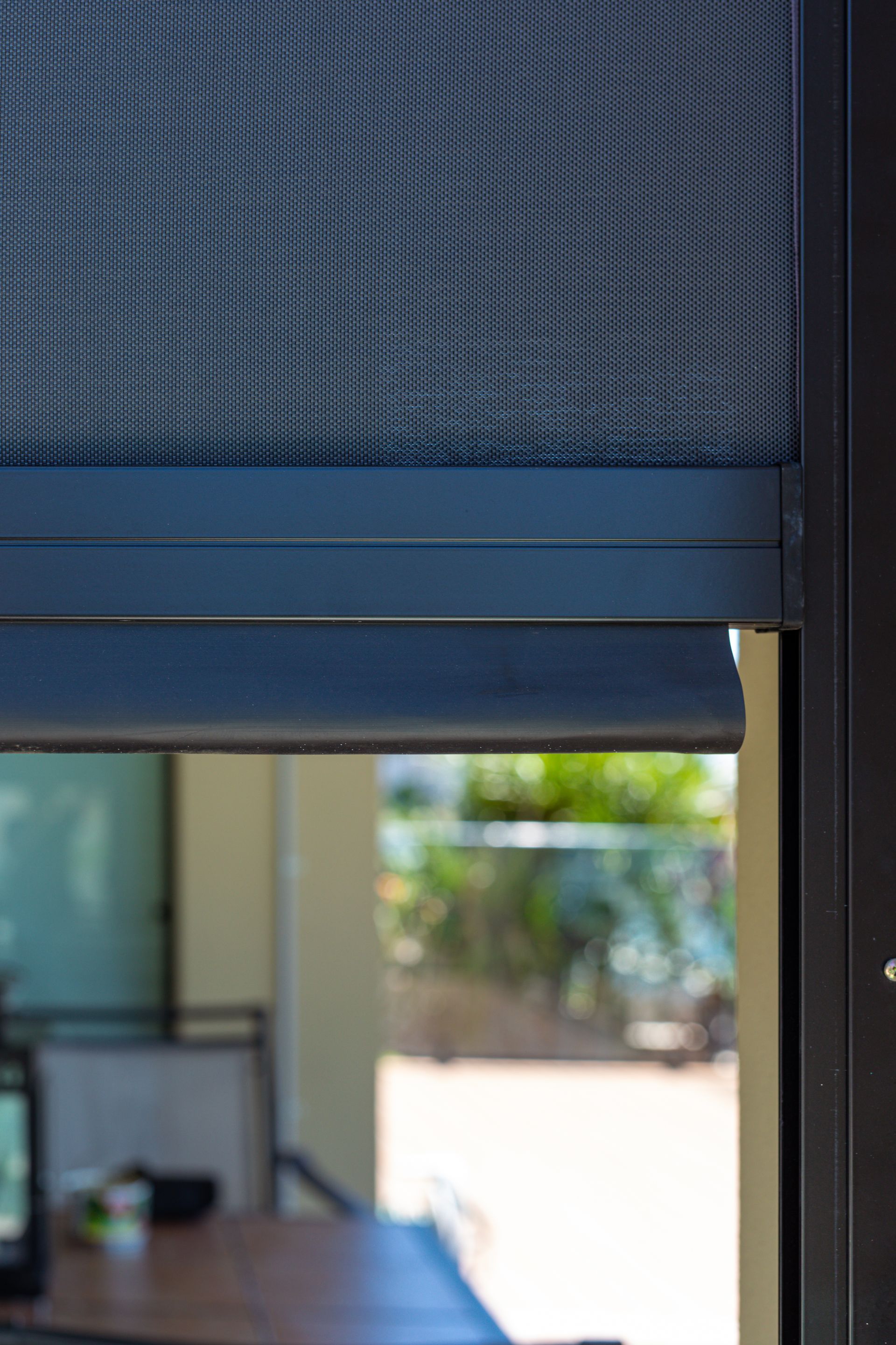 A close up of a screen door with a table in the background.