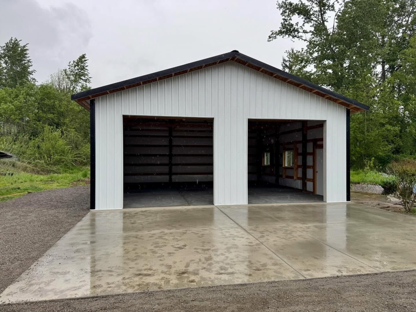 White two-car garage with open bays on a concrete pad, set against a green background.