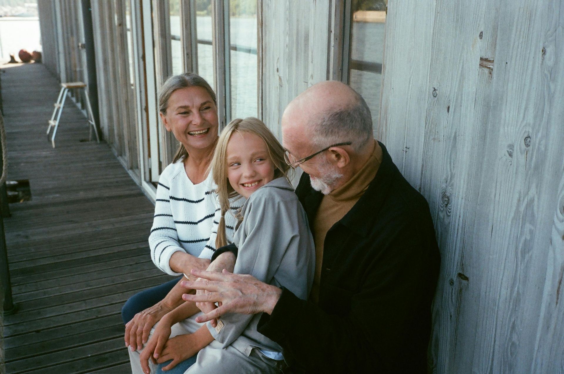 A man and a woman are sitting on a porch with a little girl.