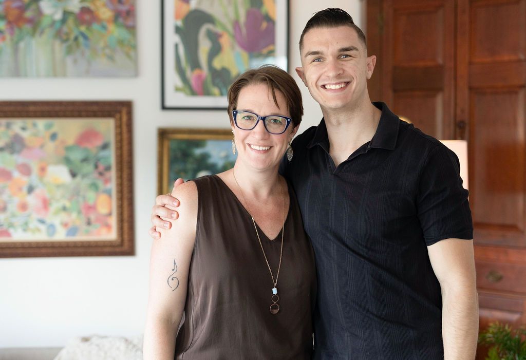 Woman with glasses and man smiling, arm around her, inside a home.