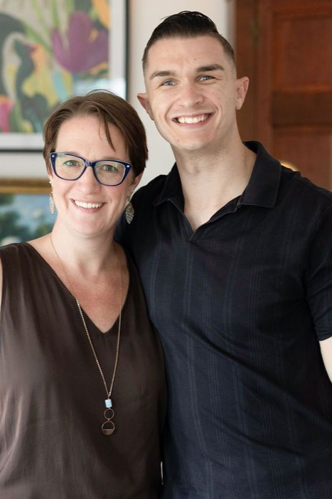 Woman with glasses and man smiling, arm around her, inside a home.