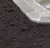 A close up of a pile of dirt next to a brick walkway.