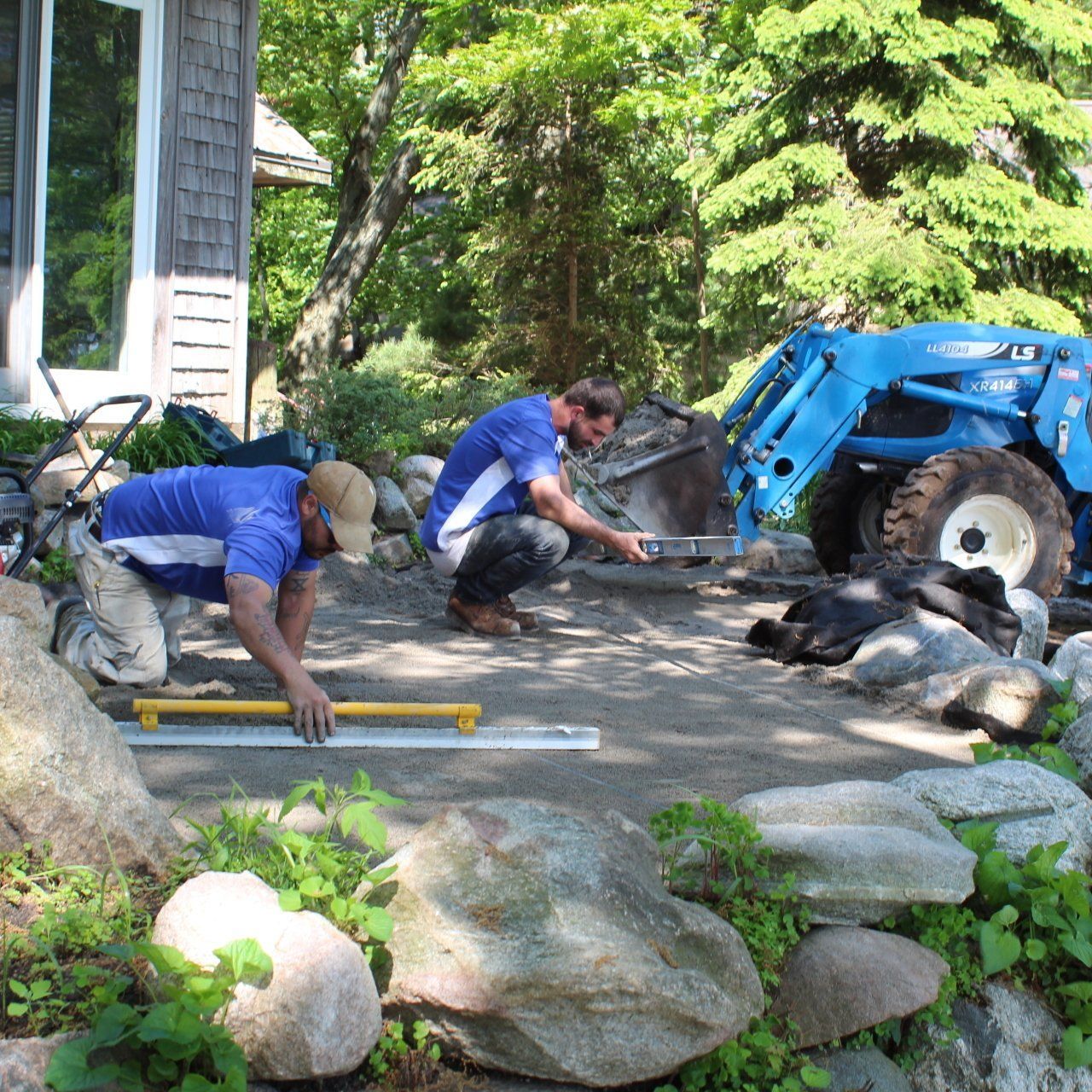 Two men kneeling down in front of a blue tractor